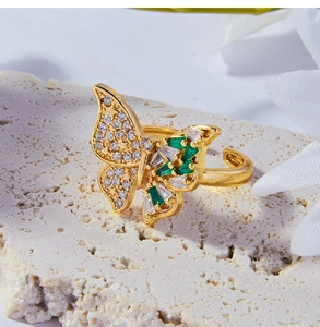 Detalle de un anillo de mariposa chapado en oro de 18k con diamantes y piedras verdes