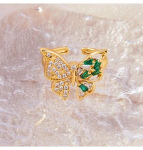 Detalle de anillo de mariposa con cristales verdes y circonitas en banda dorada ajustable