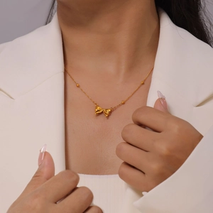 Elegante vergoldete Schleifen-Halskette mit Kugelkette an Model im weißen Blazer