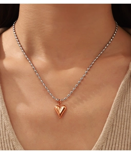 Gros plan d'un collier pendentif cœur bicolore or rose et argent sur un mannequin