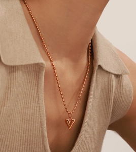 Gros plan d'un collier pendentif cœur en or rose 18k sur modèle avec chaîne perlée