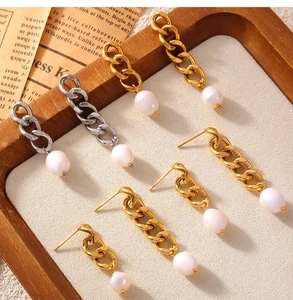 Detail of gold and silver chain tassel earrings featuring freshwater pearls in a tray