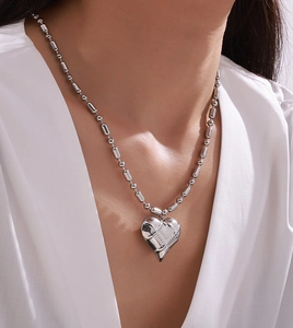 Detail of silver heart pendant with quilted texture on beaded stainless steel chain