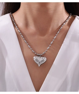 Detail of silver heart pendant with lattice texture on polished beaded necklace chain