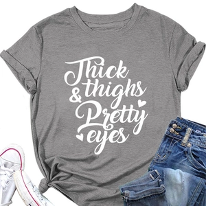 Flat lay of gray T-shirt with 'Thick thighs Pretty eyes' print and denim shorts