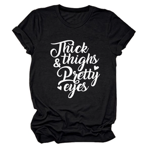 Detail of Thick Thighs Pretty Eyes lettering on black short sleeve cotton t-shirt