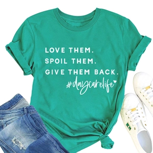 Green t-shirt with 'Love Them' print styled with blue jeans and sneakers on white background
