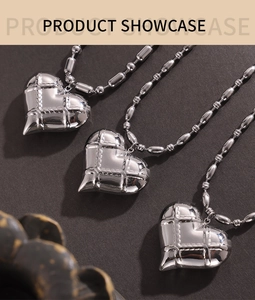 Detail of silver quilted heart pendants on beaded chains with mirror finish texture