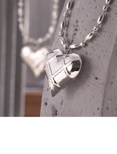 Macro shot of hollow heart pendant with grid texture on polished stainless steel chain