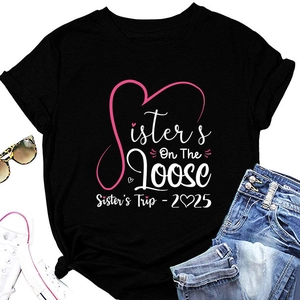 Flat lay of black round neck T-shirt with pink Sister's Trip 2025 print and knotted hem