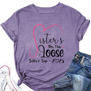 Flat lay of purple Sister's Trip 2025 t-shirt with denim jeans and sneakers