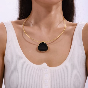 Golden snake chain necklace with black triangular onyx pendant worn by a model