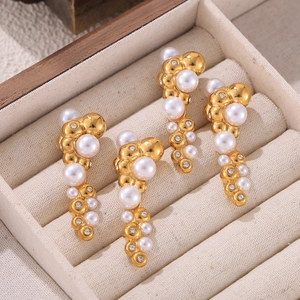 Gold-plated earrings with pearls and crystals in streamlined design on beige velvet