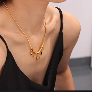 Collier en acier titane doré avec zircons et pendentifs ronds en émail noir