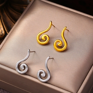 Polished gold and silver geometric spiral stud earrings displayed on jewelry box cushion