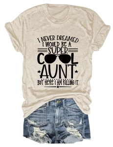 Flat lay of a beige round neck T-shirt with 'Cool Aunt' slogan and denim shorts