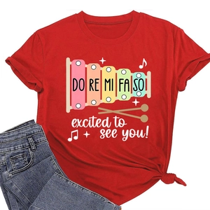 Détail d'un t-shirt rouge à col rond avec imprimé de xylophone arc-en-ciel et musique