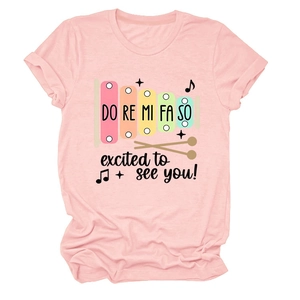 Détail d'un t-shirt en coton rose avec imprimé xylophone arc-en-ciel et notes de musique