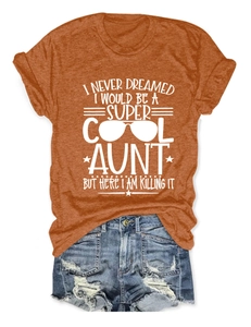 Flat lay of an orange crew neck t-shirt with Super Cool Aunt slogan and denim shorts