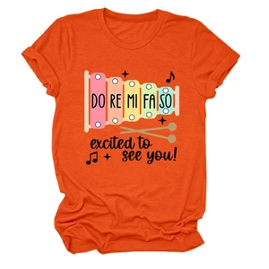 Détail d'un t-shirt orange à col rond avec imprimé de xylophone coloré et gamme musicale