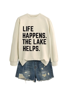 Detail of white crewneck sweatshirt with 'LIFE HAPPENS' text and distressed denim shorts