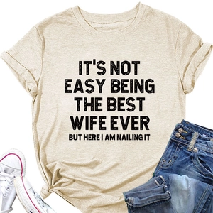 Détail d'un t-shirt abricot montrant l'imprimé It's Not Easy Being the Best Wife au milieu