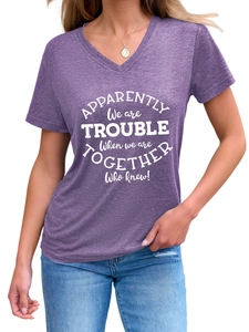 Detail of purple V-neck T-shirt showing artistic white lettering and textured knit fabric