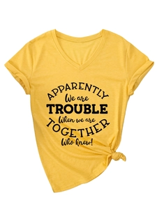 Detail of yellow V-neck T-shirt showing printed text graphic and side knot detail