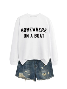 Dettaglio della felpa bianca con stampa nera 'SOMEWHERE ON A BOAT' e pantaloncini di jeans