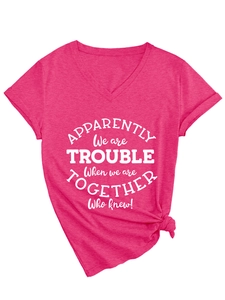 Detail of magenta V-neck T-shirt with white text print and stylish knotted hem design