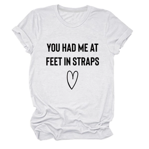 Detail eines weißen T-Shirts aus Baumwollmischung mit schwarzem You Had Me At Feet-Aufdruck
