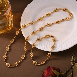 Minimalist 18k gold plated ball chain necklace and bracelet set on a white ceramic plate