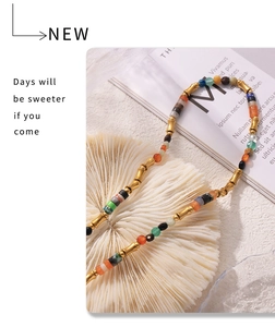 Détail de perles de pierre naturelle colorées et de maillons en bambou doré sur un collier
