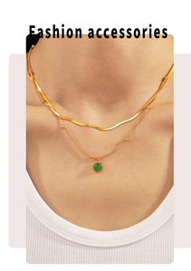 Détail d'un collier double rang doré avec pendentif en pierre verte sur le mannequin