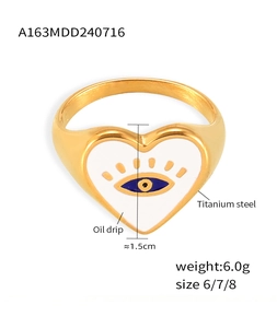 Macro detail of gold-plated titanium heart ring with white oil drip and evil eye motif