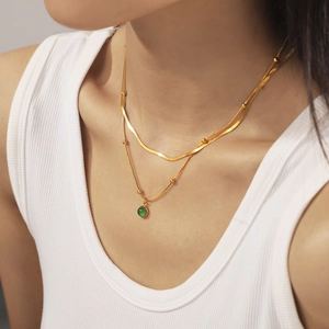 Collier double couche doré vintage français avec pendentif vert sur débardeur blanc