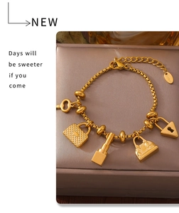 Detailed close-up of 18K gold plated charms including key and bag on a gold box chain
