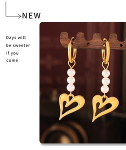 Détail de boucles d'oreilles cœur en or 18 carats avec perles sur un présentoir en bois