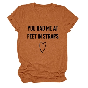 Detail eines rostroten T-Shirts mit YOU HAD ME AT FEET Text und Herzgrafik aus Baumwolle
