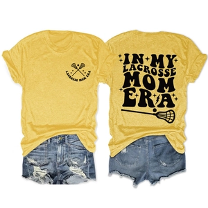 Close-up of In My Lacrosse Mom Era text and hockey sticks graphic on yellow t-shirt