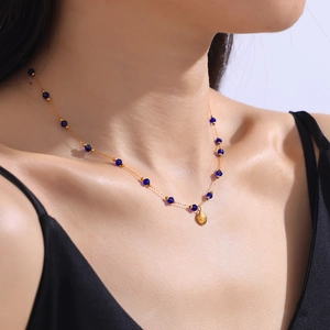 Elegante collana dorata con perline blu e ciondolo a conchiglia su una modella