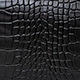 Close-up of black crocodile pattern faux leather texture with matte finish for handbag