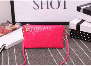 Detail of rose red crocodile embossed mini crossbody bag with gold hardware and strap