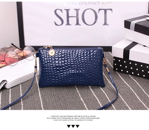 Detail view of navy blue crocodile pattern crossbody bag with golden metal zipper tag