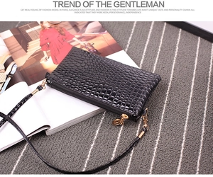 Detail of black crocodile texture small crossbody bag on fashion magazine background