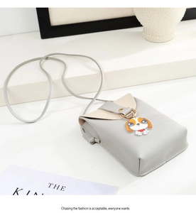 Detail view of mini crossbody bag with a cute dog pendant and golden ring ornament