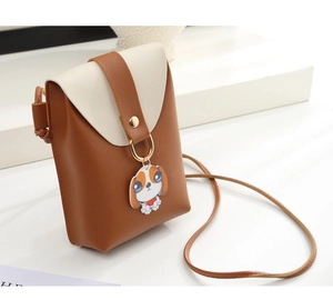 Close-up of a mini crossbody phone bag with dog charm and gold ring buckle detail