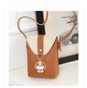Detail of a mini crossbody phone bag with color-block flap and cute dog charm on desk