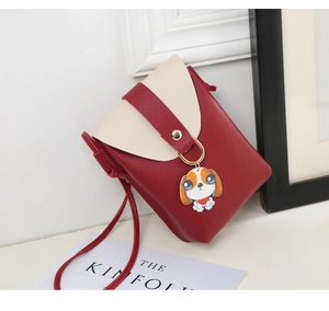 Detail view of mini red crossbody bag with cute dog pendant and golden metal ring