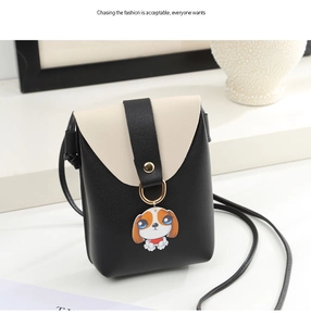 Detail of a minimalist black and white leather crossbody bag with cute cartoon dog charm